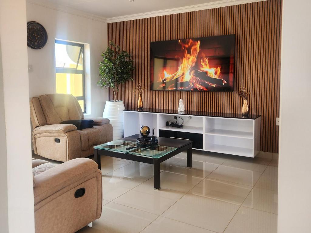 a living room with a fireplace with a tv above it at The Pebbles-UA in Mahikeng