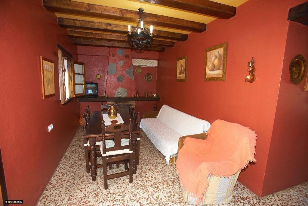 sala de estar con paredes rojas, sofá y mesa en Casa del Huerto, en El Bosque