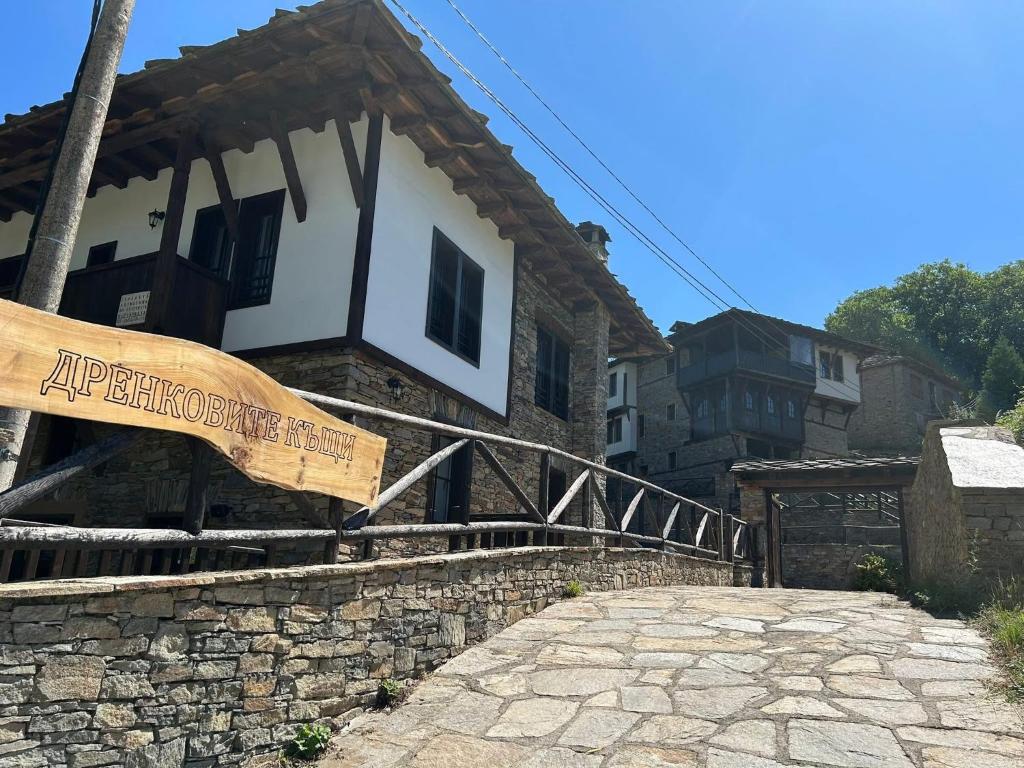 a building with a wooden sign on the side of it at Дренковите Къщи Drenkovi Houses in Kovačevica