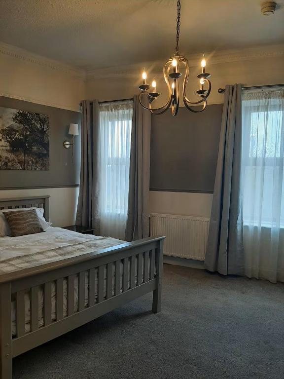a bedroom with a large bed and a chandelier at Stonehouse Apartment in Mexborough