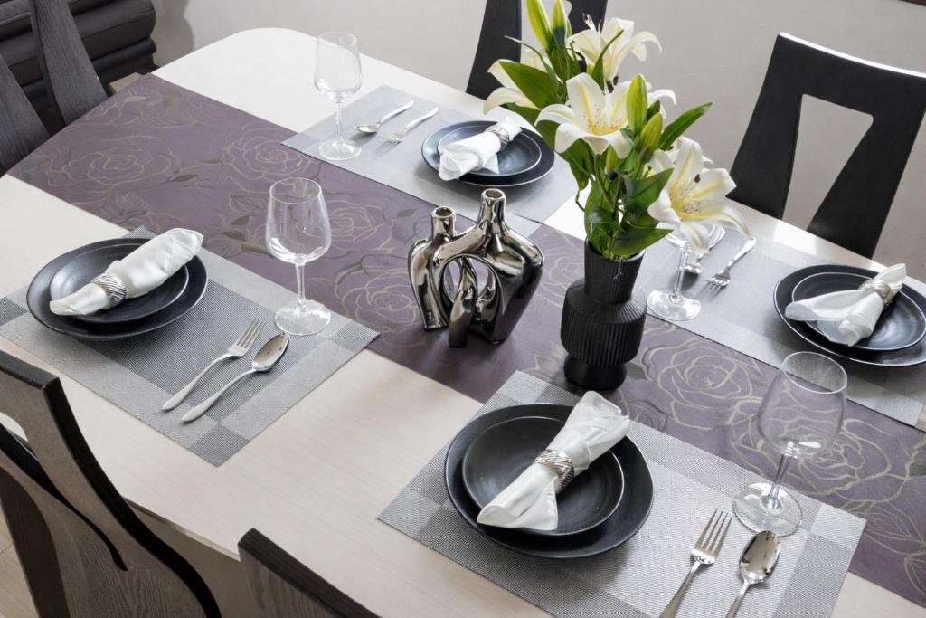 a table with black plates and a vase with white flowers at A Family Friendly Spacious Villa - Easy to Tokyo Station & Conveniently Located for Tokyo Disney Resort & 1 min to Convenience Store in Tokyo
