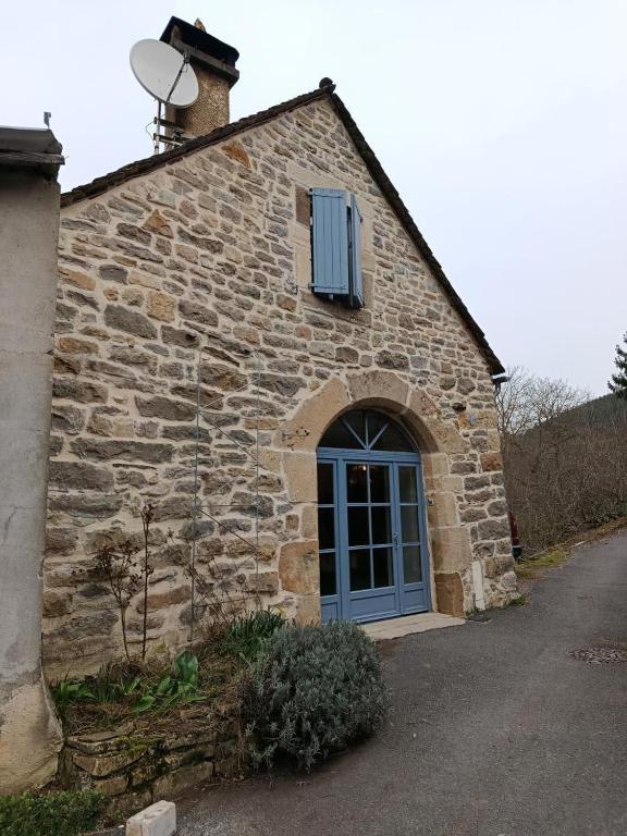 a stone building with a blue door and a window at L'ecrin de séraphie in Nojaret