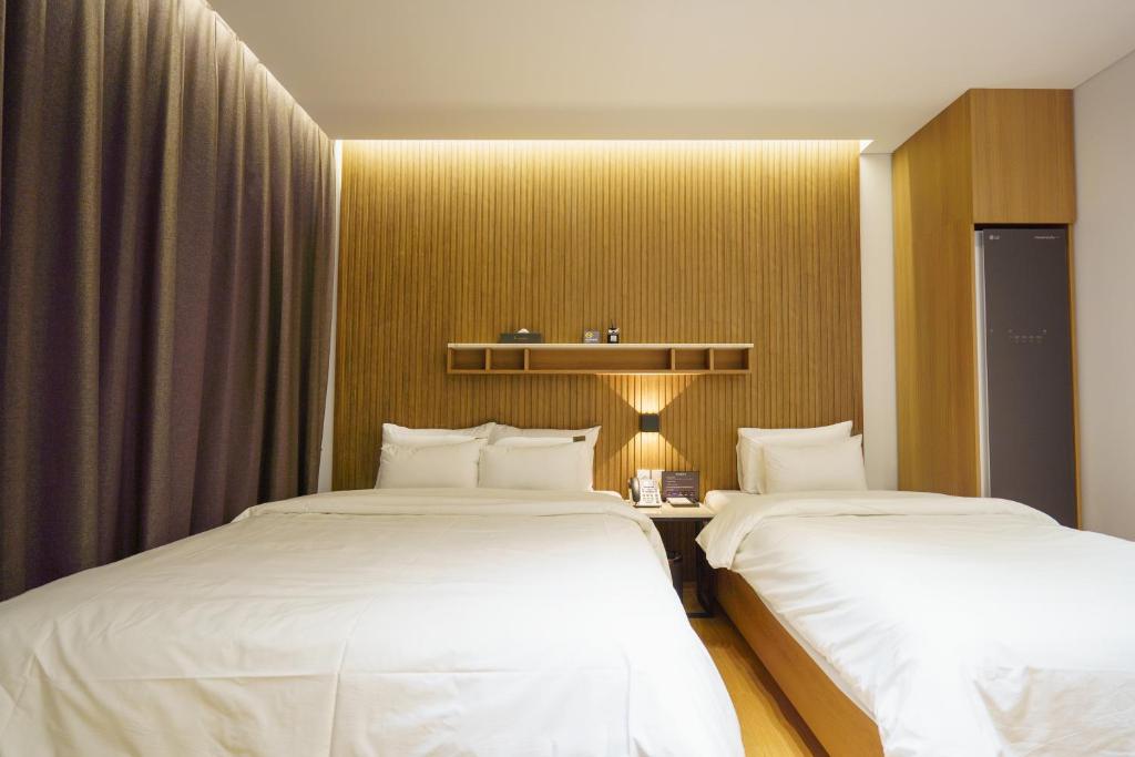 two beds in a hotel room with white sheets at Hotel Hariu in Gwangju