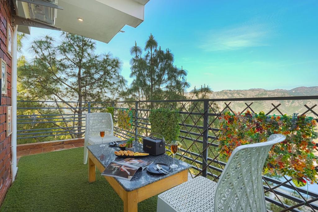 a balcony with a table and two chairs and a view at Nirvana By Nest Kasauli 2 BHK Luxury Apartment Rooftop Cafe Free Parking in Kasauli