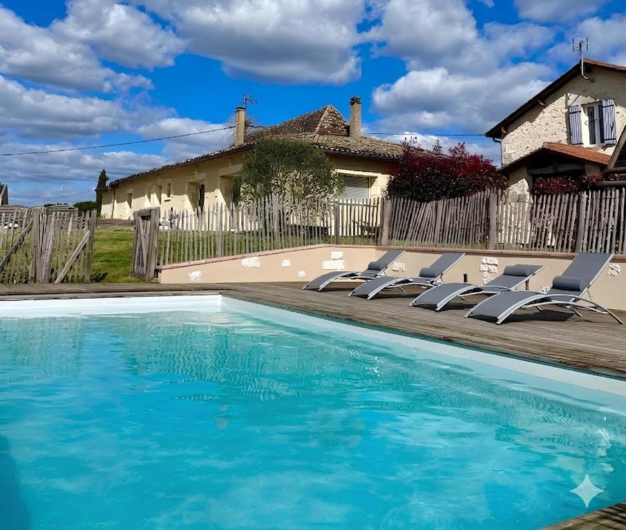 a swimming pool with chairs and a house at Les Marchettes in Saint-Nexans