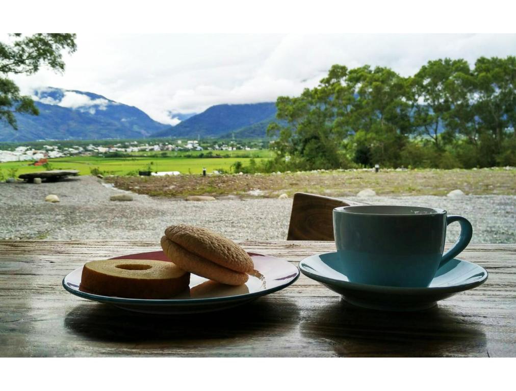 a table with a cup of coffee and a plate of bread at Ikegami Dapo Moutain Bed and Breakfast in Chishang