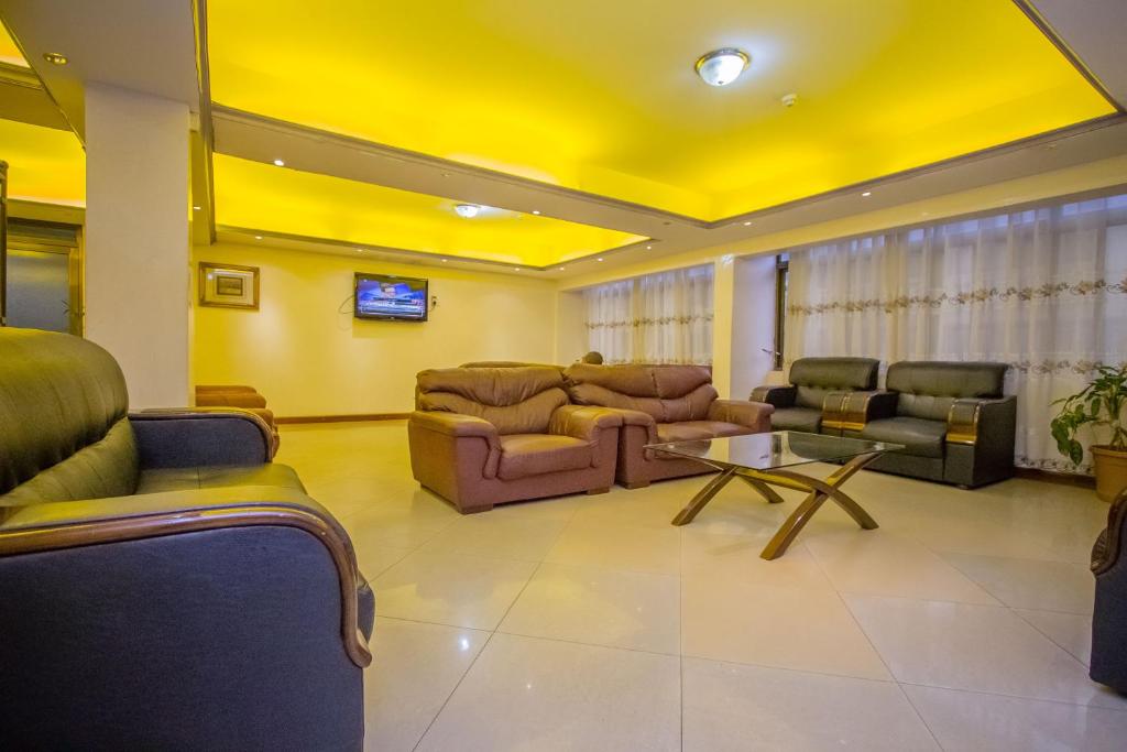 un soggiorno con divani, tavolo e soffitti gialli di Holiday Express Hotel Kampala a Kampala