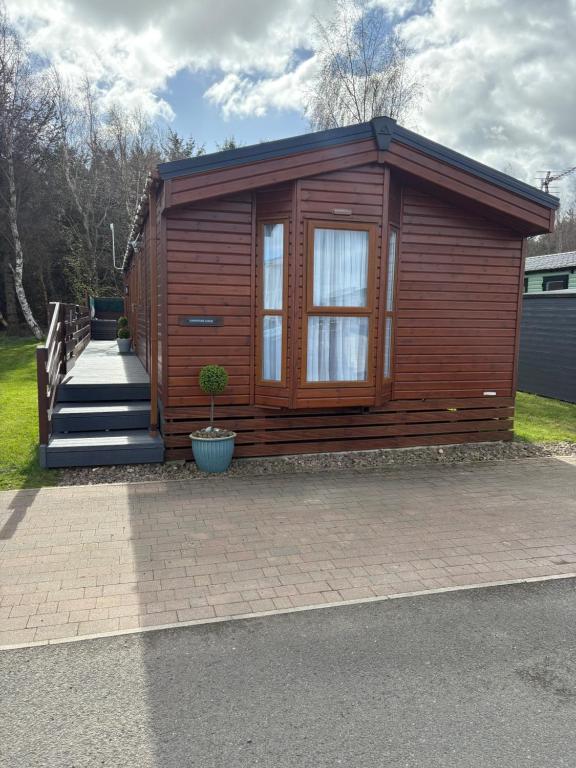 a small wooden cabin with a staircase in a yard at Longstone Lodge in Morpeth