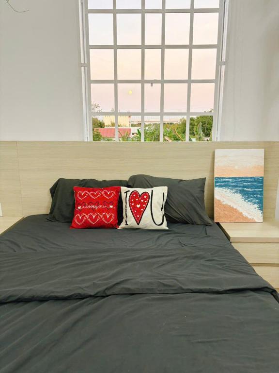 a bed with three red and white pillows on it at Mya's Homestay in Long Trường