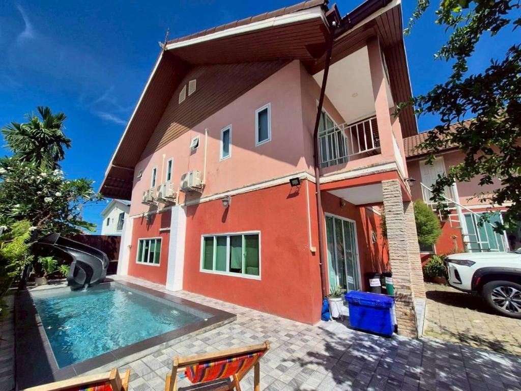 a house with a swimming pool in front of it at Baan Pink Pool Villa Pattaya in Ban Huai Yai