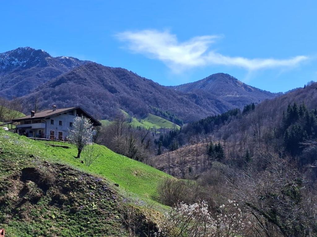 a house on a hill with mountains in the background at B&b CASCINA CORNELLA in Cremeno