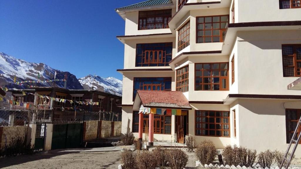 a large white building with mountains in the background at Hotel Heritage in Kaza