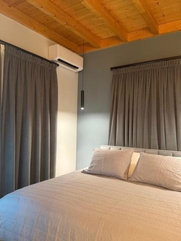 a bedroom with a large bed with gray curtains at Pastorian Hotel in Maliq