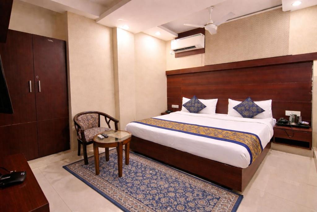 a bedroom with a bed and a table and a chair at Mauryan Elite Hotel Vasant Kunj in New Delhi