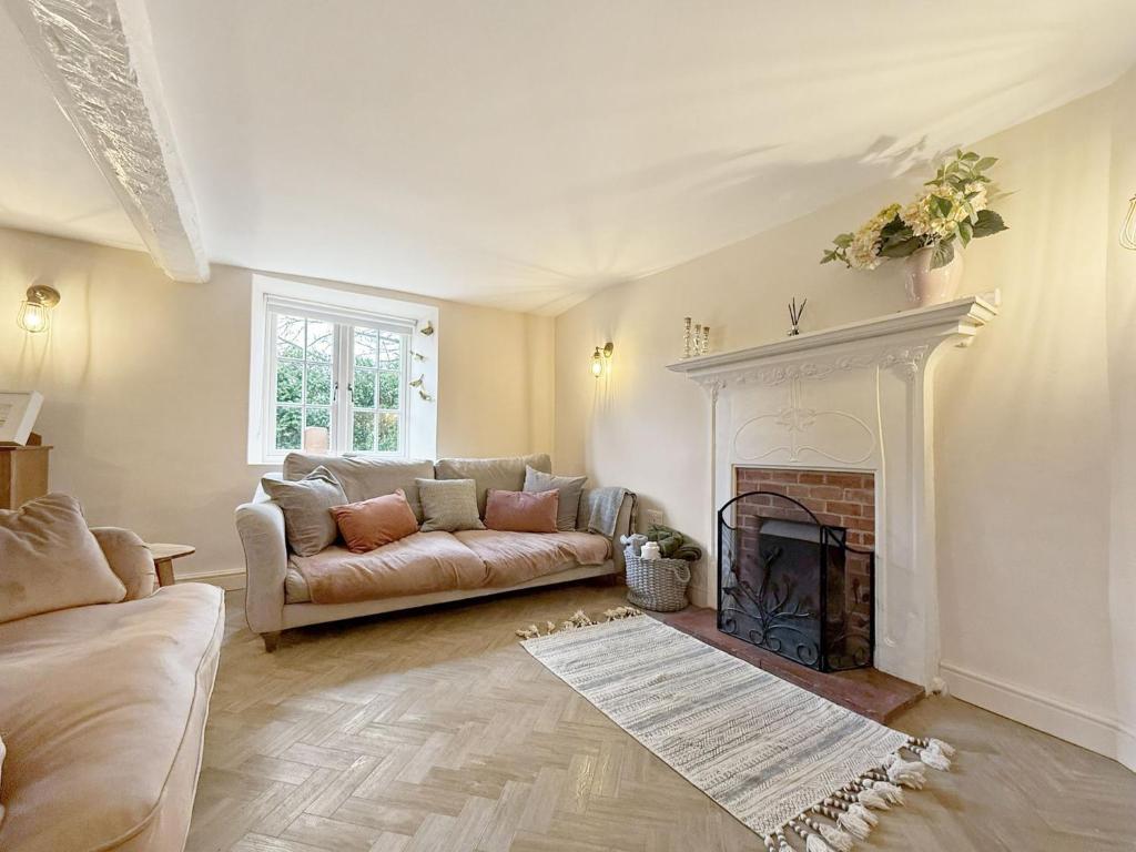 a living room with a couch and a fireplace at Vine Cottage in Thornham