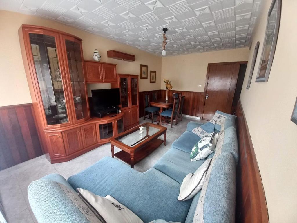 a living room with a blue couch and a table at Casa O Capitán in Corcubión
