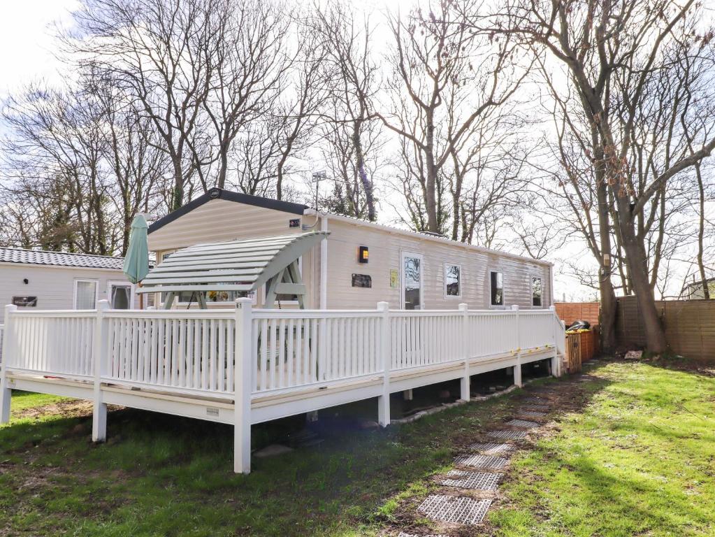 a white mobile home with a white fence at Sunflower Retreat, Caravan 61 in Morpeth