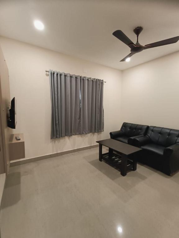 a living room with a black couch and a ceiling fan at Comfort nest in Manipal in Manipal