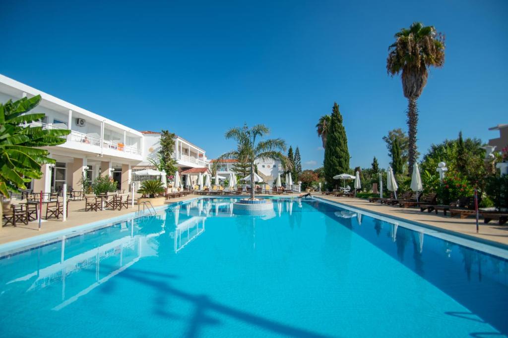 a large swimming pool with chairs and a building at Premium ikaros in Laganas
