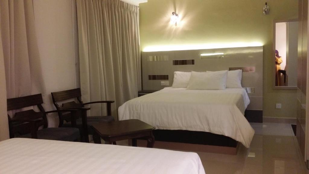 a hotel room with two beds and a chair at Staycity Apartment - D'Perdana Sri Cemerlang in Kota Bharu