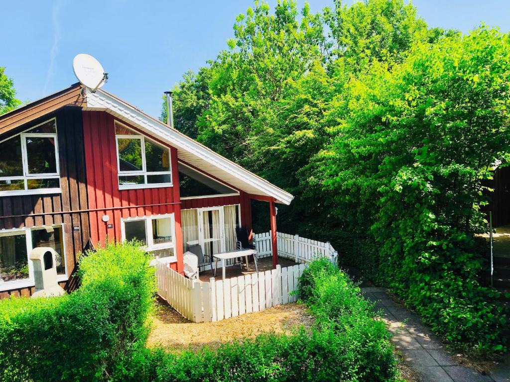 a red house with a white fence and trees at Extertal Ferienpark Haus Sonnental in Extertal
