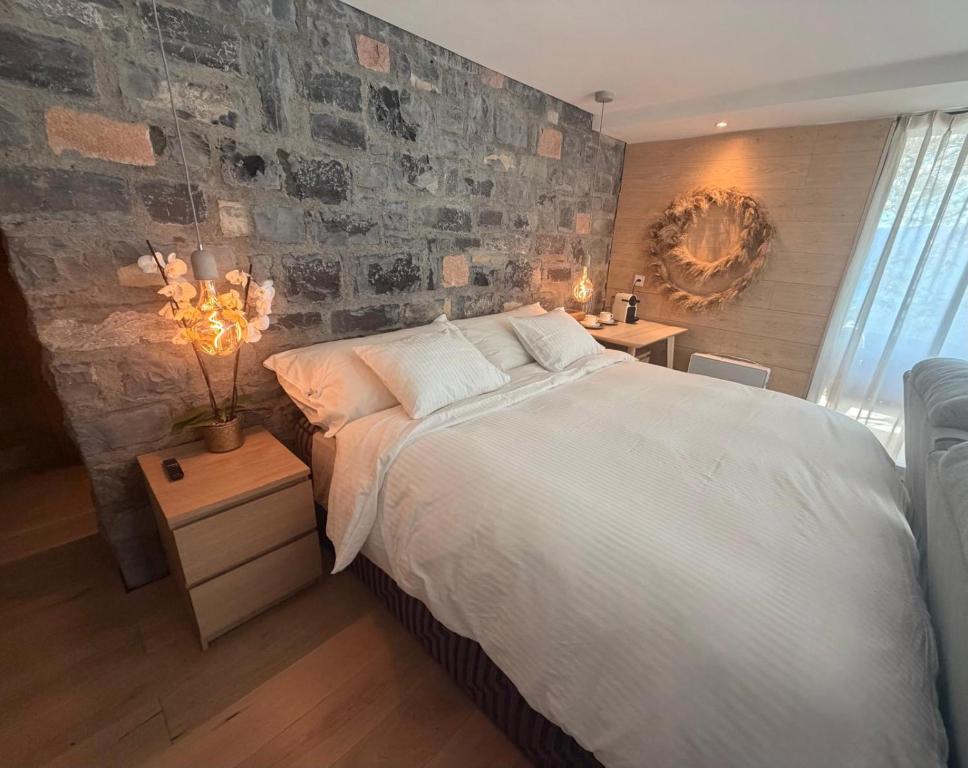 a bedroom with a large bed and a stone wall at ROMANTIC SUlTE WITH ITS OWN SPA AND OPEN VIEW TO LUGANO in Cademario