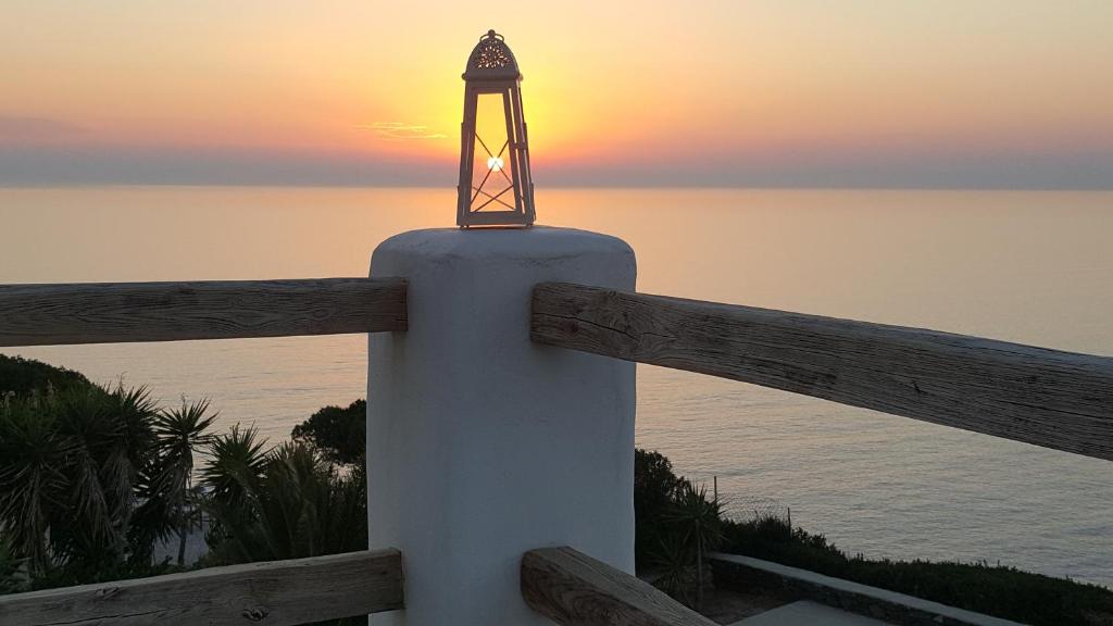 une lumière sur un pôle avec le coucher du soleil en arrière-plan dans l'établissement Syros Apartments Suites Chryssonisos Kini, à Kinion