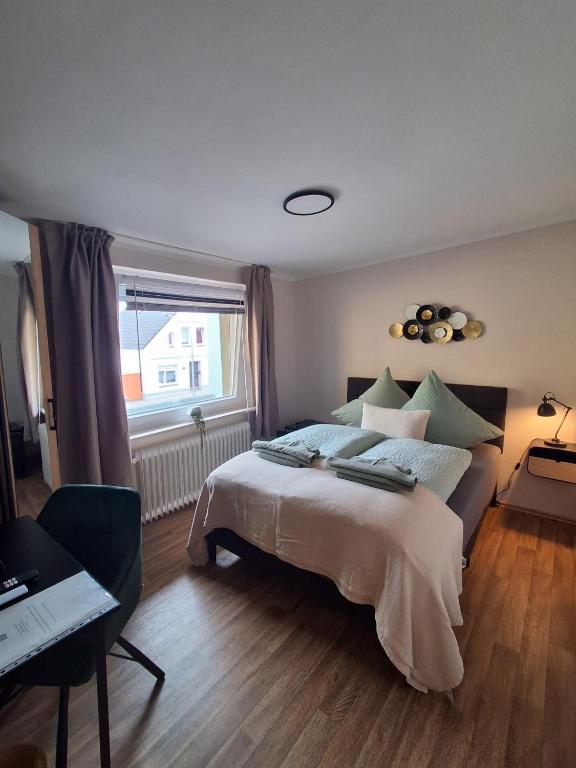 a bedroom with a bed and a desk and a window at STEP IN Apartments ! in Wilhelmshaven
