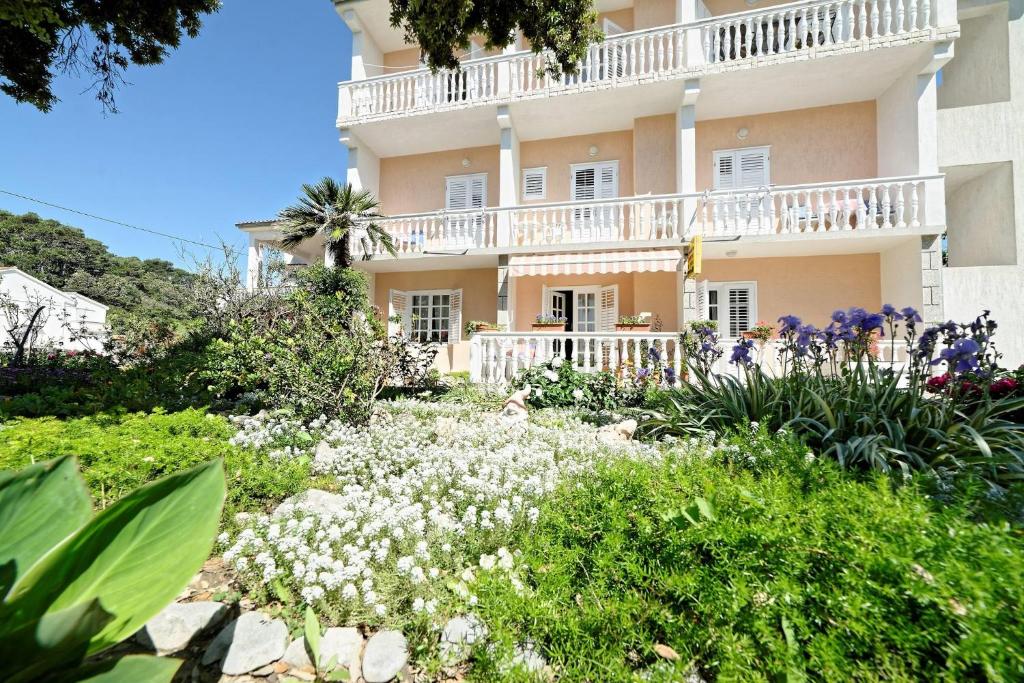 a building with a flower garden in front of it at Rooms Milica in Palit