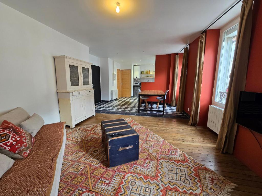 a living room with red walls and a suitcase on the floor at La Grande Glycine in Coulommiers