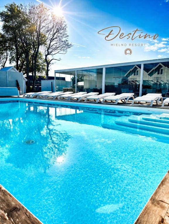 a swimming pool with blue water in front of a building at DESTINO wakacyjne domki-dwa podgrzewane baseny-drink bar in Mielno