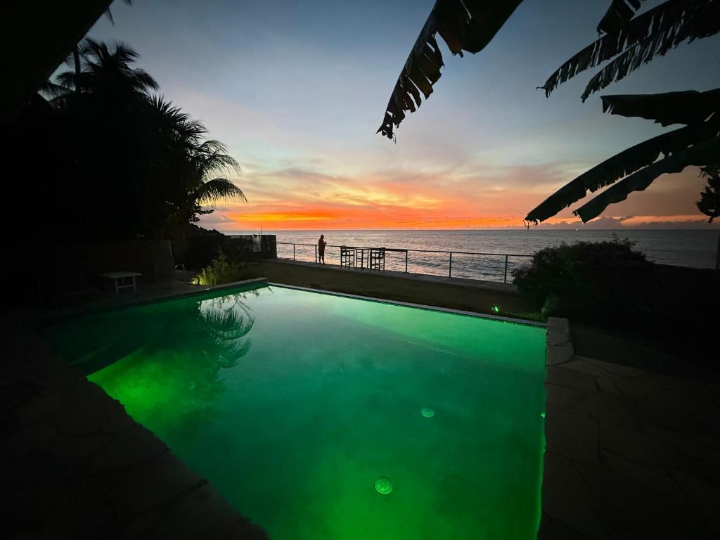 a swimming pool with a view of the ocean at sunset at On the Beach in Black Rock