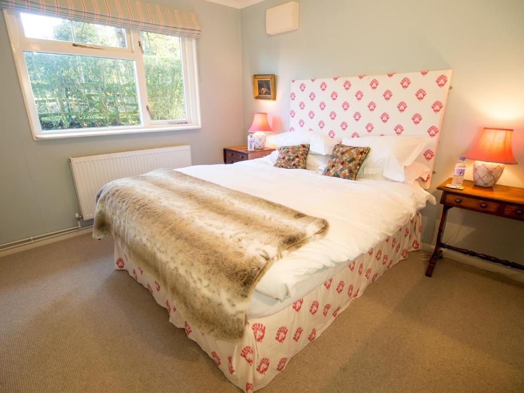 a bedroom with a large bed with a large window at Yew Tree Cottage in Maidford