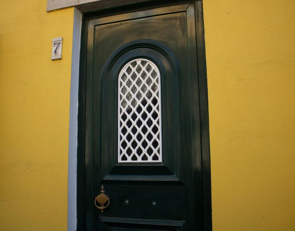 a green door with a window on a yellow wall at Casa 7 in Sintra