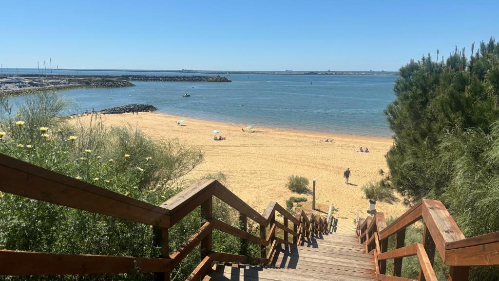 a wooden staircase leading to a beach with people on it at Apartamentos Amy 3 con vista a mar in Palos de la Frontera