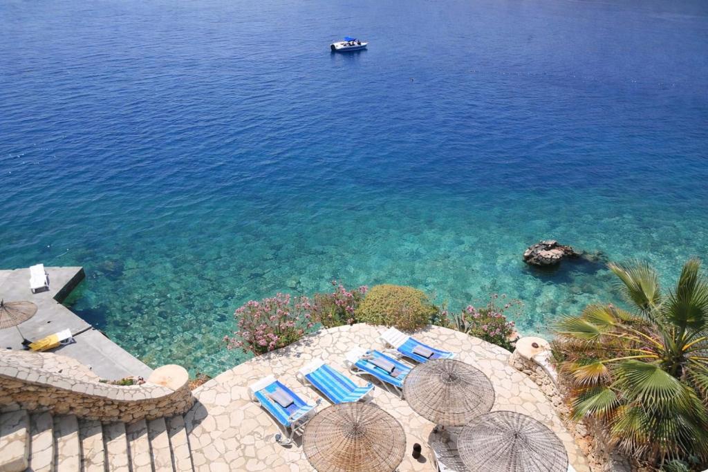 an aerial view of a beach with chairs and a boat at Cactus Garden Kalkan - Private Mediterranean Home at Club Patara in Kalkan