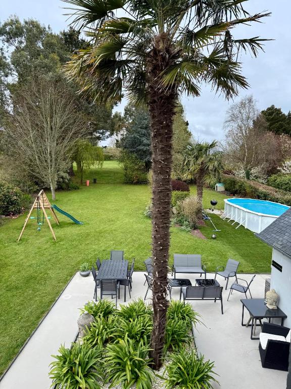 a palm tree with chairs and a playground at Villa Bretagne 5 chambres doubles 3 SDB in Plérin