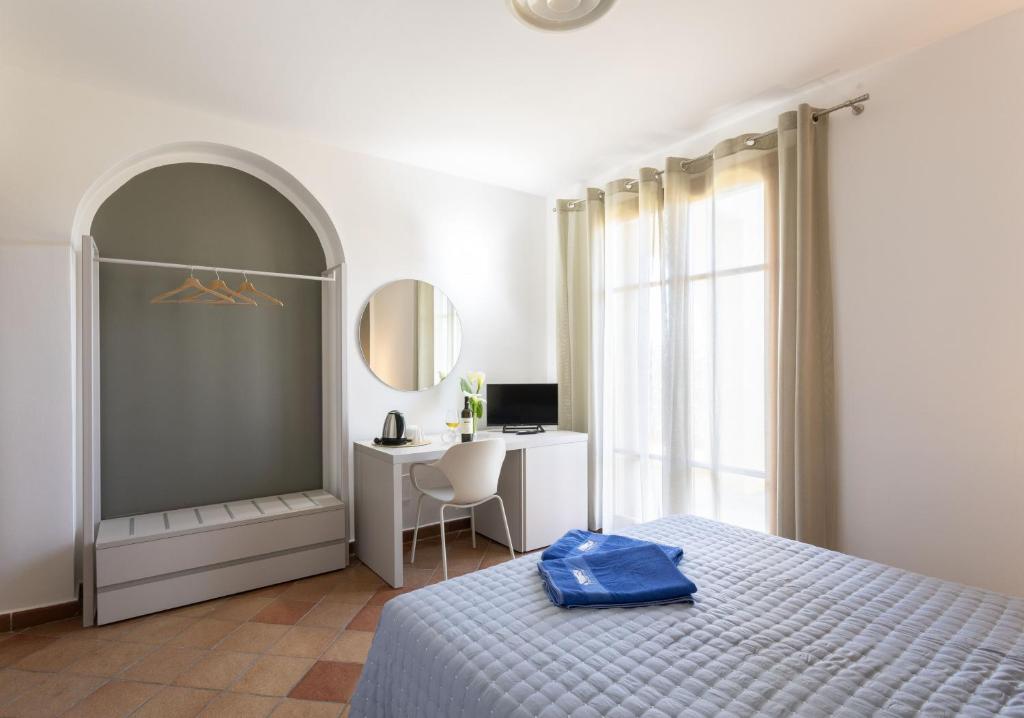 a bedroom with a bed and a desk and a mirror at Podere San Michele Cantina con Camere in San Vincenzo