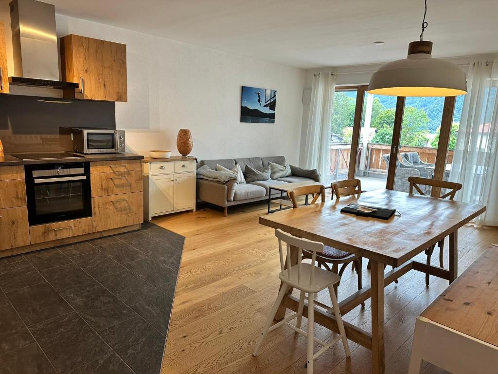 a kitchen and living room with a wooden table at Apartment Seeglück am Schliersee - modern, zentral, perfekt für Familien in Schliersee