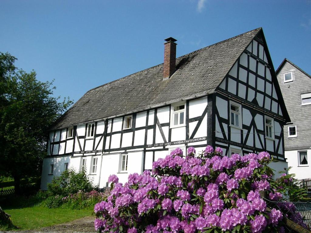 a black and white house with purple flowers in front of it at Knochenhaus in Schmallenberg