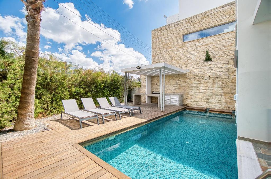 a pool with chairs and a table next to a house at DownTown Villa 2 in Paphos