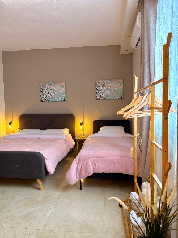 two beds in a bedroom with pink sheets at Sunny apartment 1 in Serres