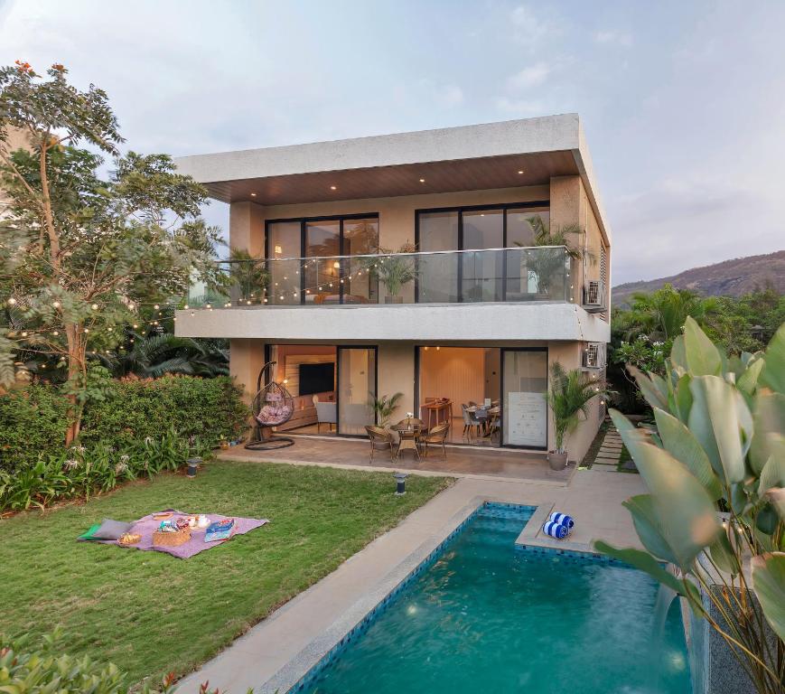 a house with a swimming pool in front of it at Saffron Stays Augustus in Karjat