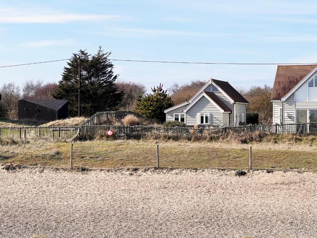 a house with a fence in front of a yard at Spinney's Boathouse by The Suffolk Cottage Collection in Thorpeness