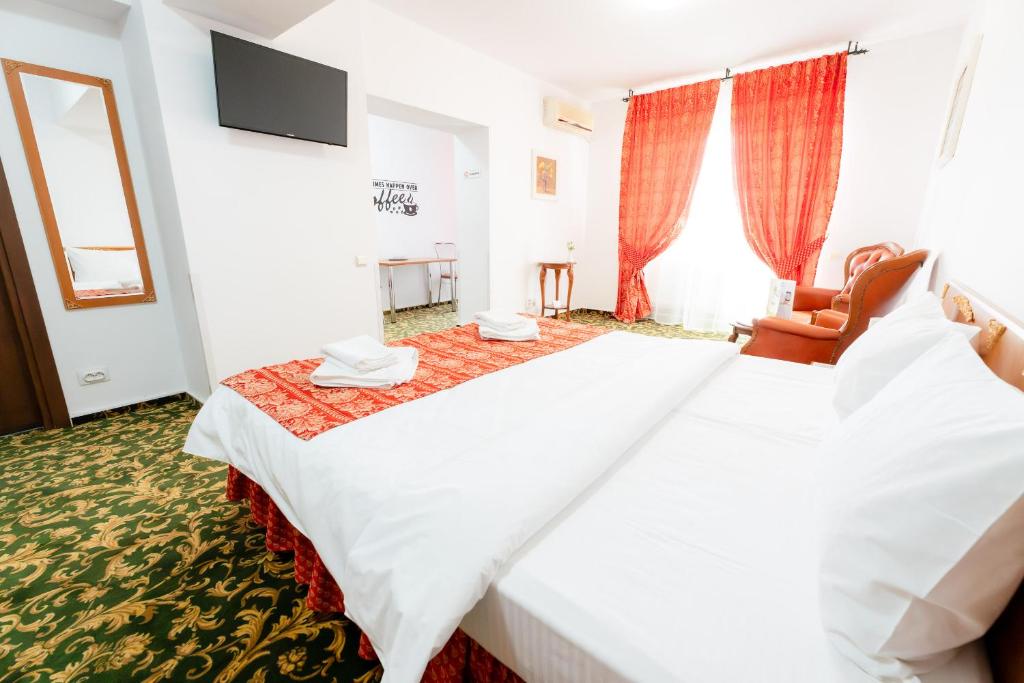 ein Hotelzimmer mit einem großen weißen Bett und einem Stuhl in der Unterkunft West Gate Studios in Bukarest