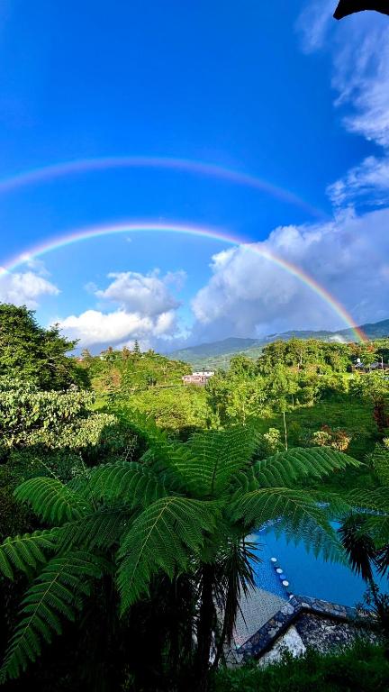 a rainbow in the sky over a lake with a forest at Hotel Villa Aventura in Cuetzalán del Progreso