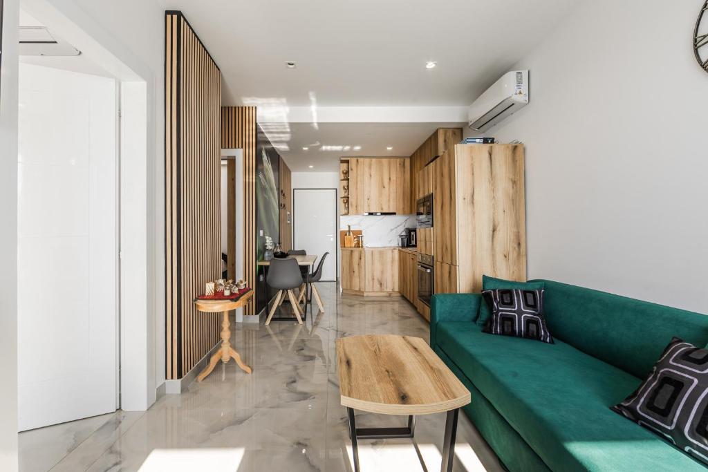 a living room with a green couch and a kitchen at The Butterfly Apartment | Seafront & Amazing Views by PikHost in Lezhë