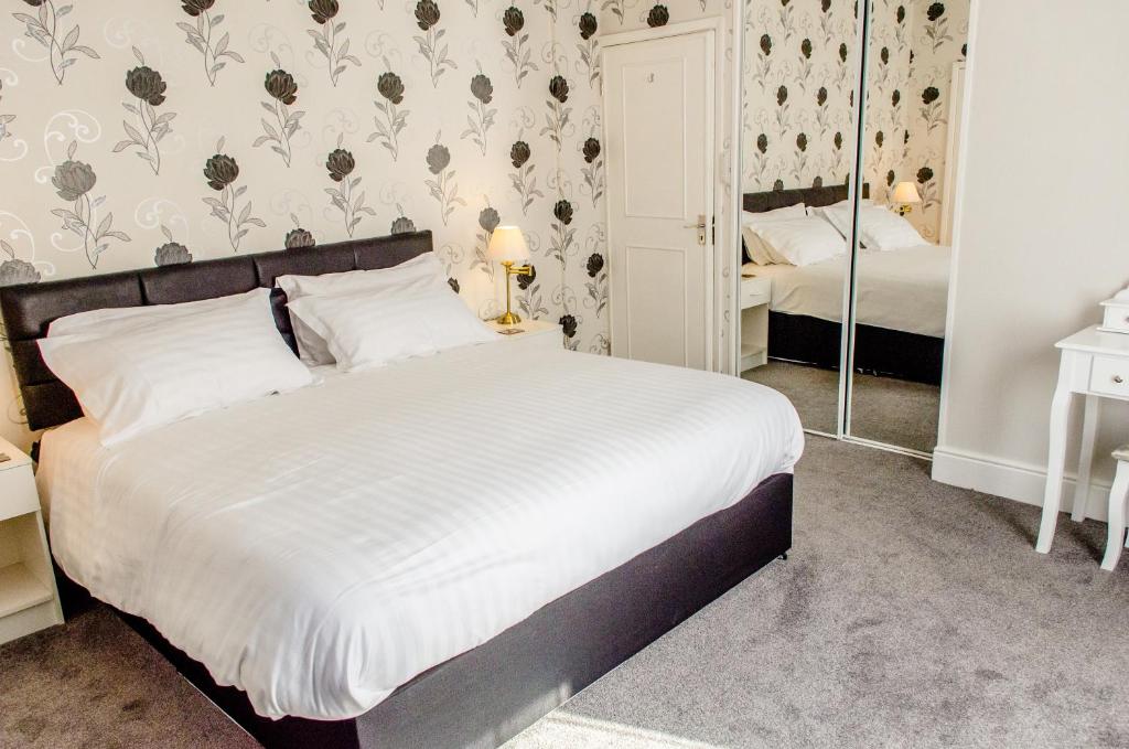 a bedroom with a large white bed with floral wallpaper at The Avenue in Shanklin