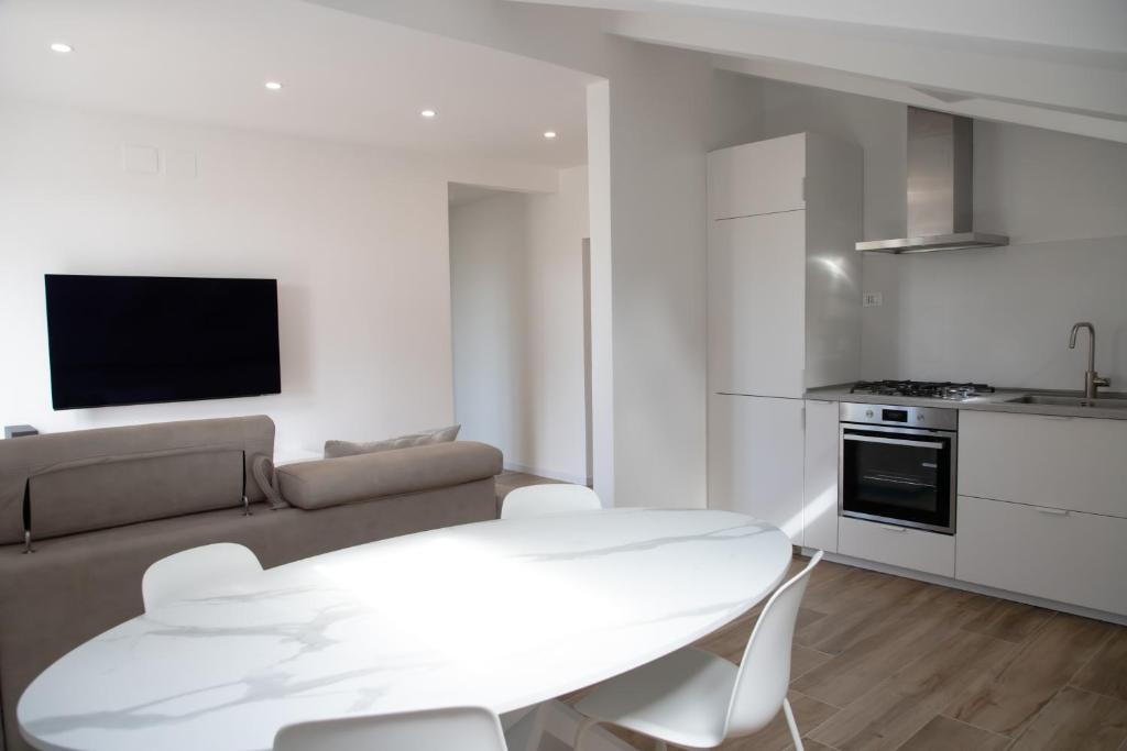 a white living room with a table and a couch at Villa Serena - Armonia Apartment in Tirrenia