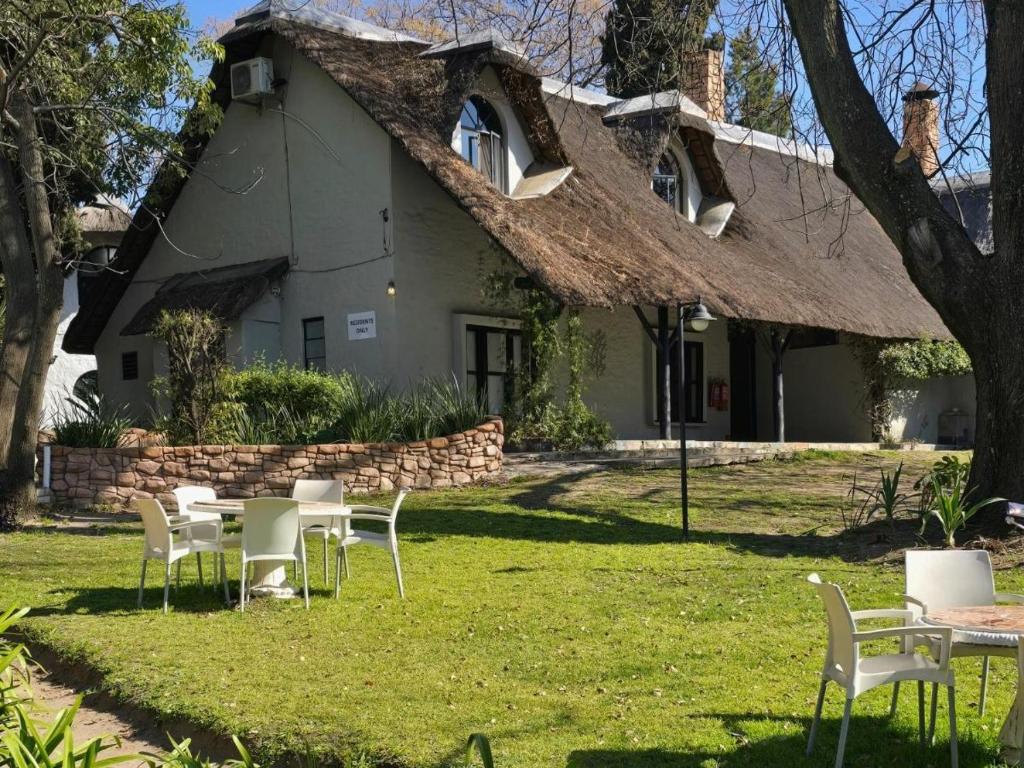a house with a thatched roof with tables and chairs at Beverly Hills Lodge in Fourways